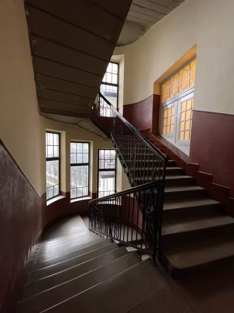 Elegant indoor staircase with classic design elements featuring windows and railings.