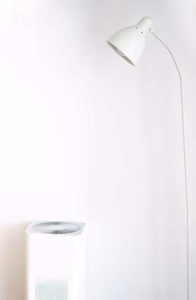 A minimalist room featuring a white floor lamp and air purifier against a blank wall.