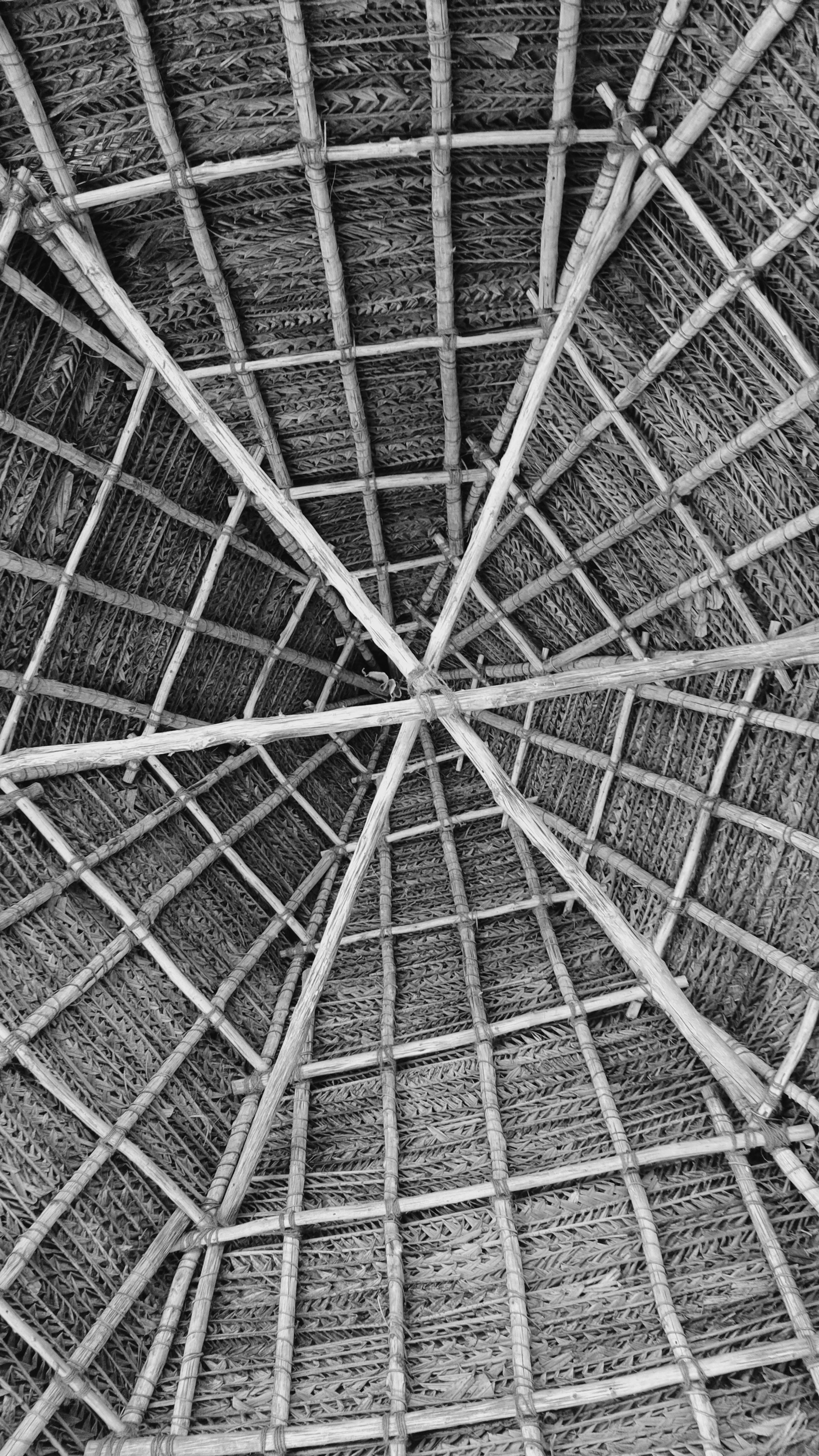 Intricate geometric patterns of an indoor bamboo thatched roof, captured from below.
