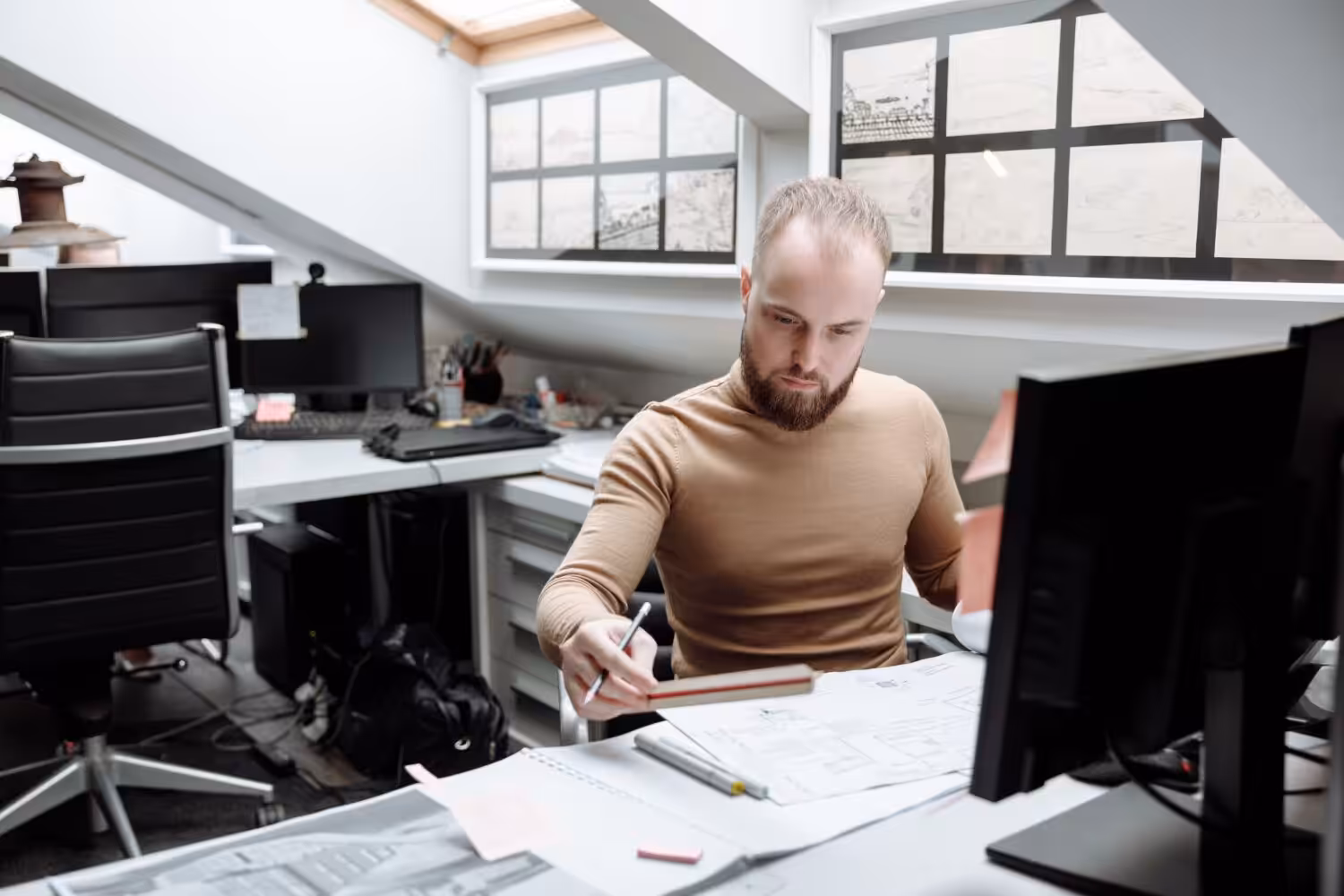 Architect focused on project designs in a bright, modern office space. Ideal for business or design themes.