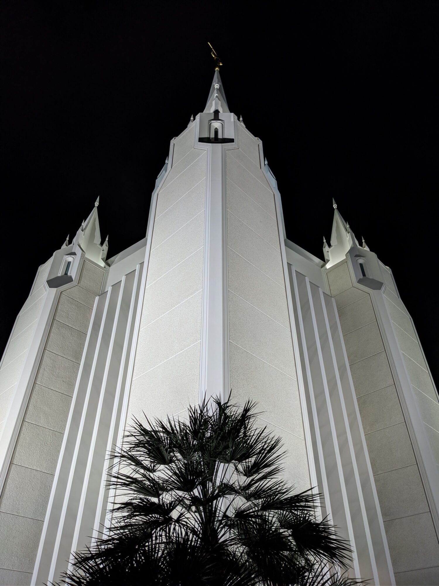 Striking low-angle nighttime view of the San Diego California Temple against a dark sky.