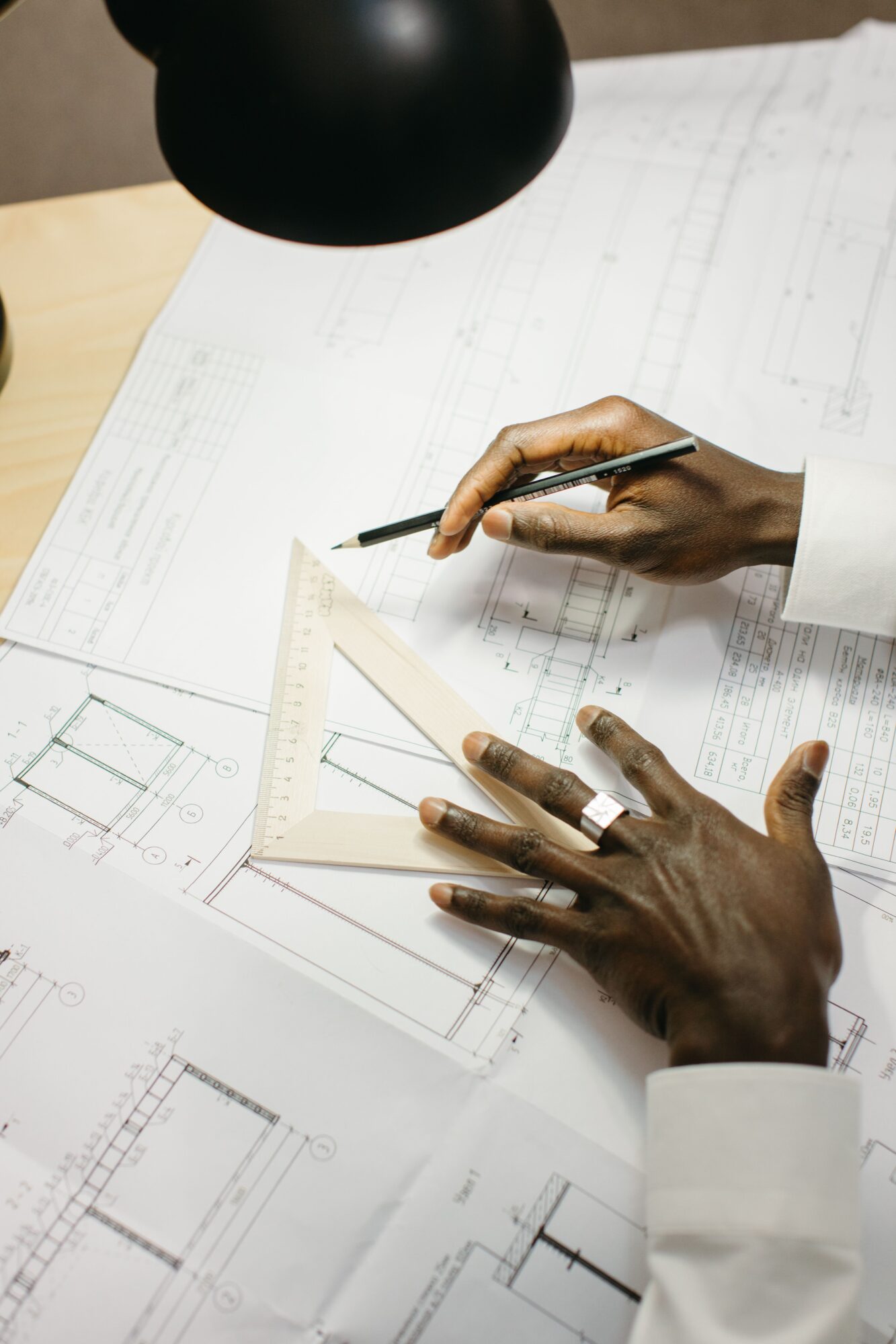 Architect drafting technical plans at a desk, focused on precision and detail.