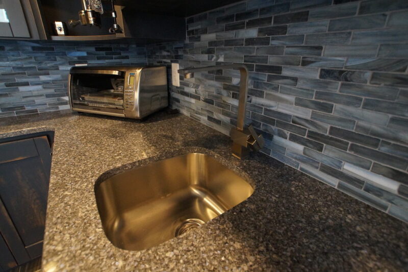 Close-up of bar sink with glass tile backsplash