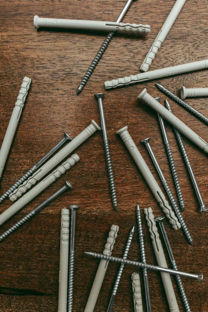 Scattered screws and nylon anchors on a wooden table, ideal for hardware and construction themes.