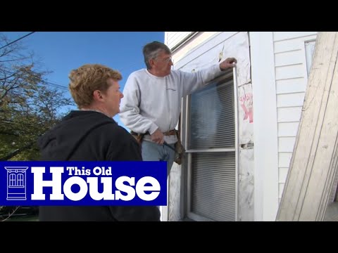 Two professionals installing window casing around vinyl siding