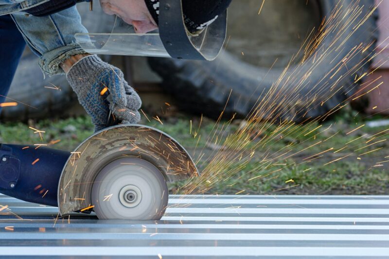 a man grinds a piece of metal with a grinder