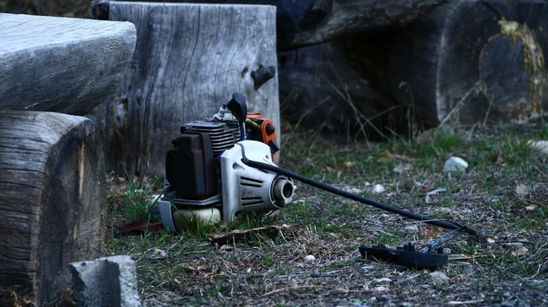 A broken chainsaw lies on the ground.
