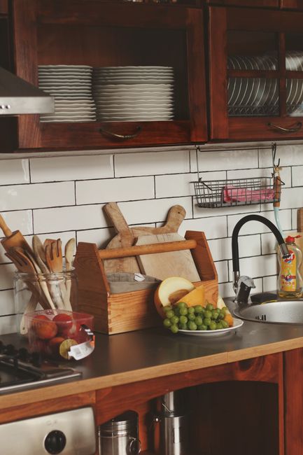 Rustic kitchen scene with warm-toned wood-effect tiles as backsplash blending naturally with white cabinets and wooden utensils - photo by Ioana Motoc