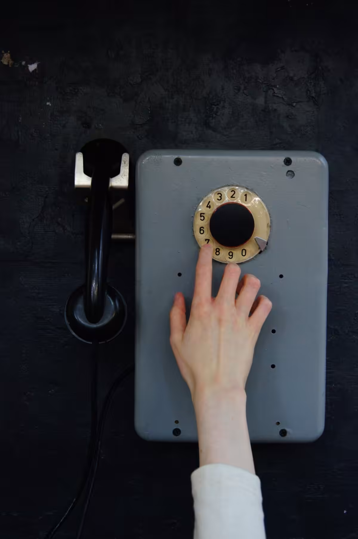 Retro rotary phone on wall with hand dialing. Captures classic technology essence in Sankt-Peterburg, Russia.