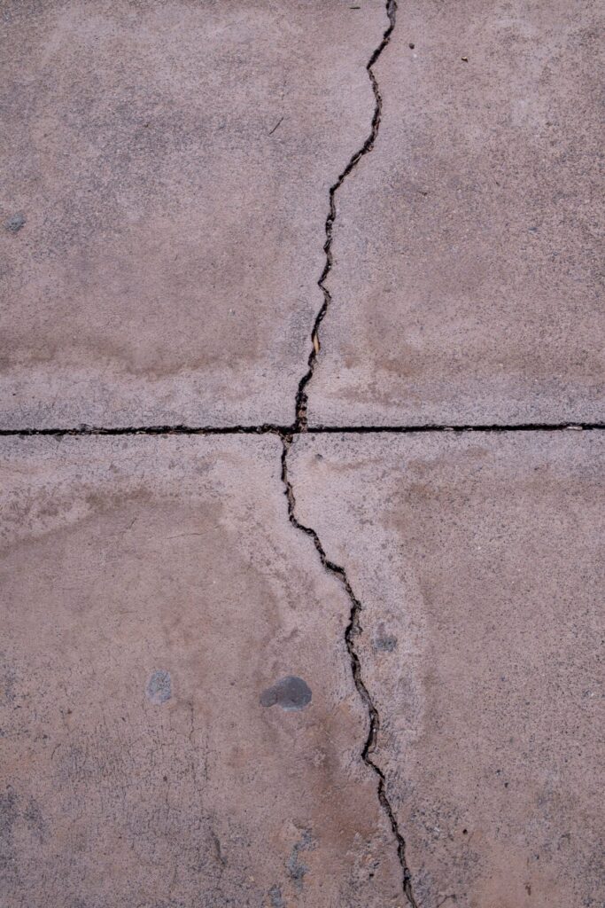 Close-up view of a cracked concrete surface showcasing natural texture and weathered appearance.