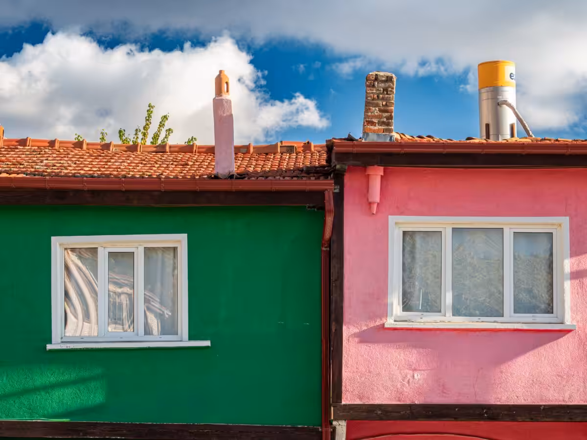 Bright green and pink houses with tiled roofs under a blue sky. Perfect for real estate or architecture themes.