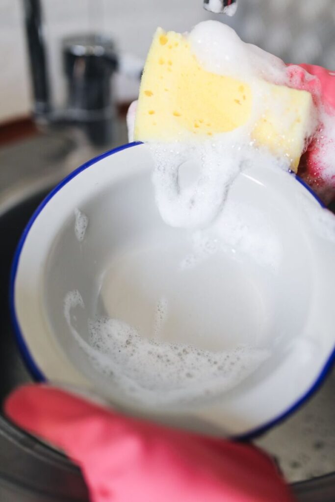 Washing a bowl with a yellow sponge and soap bubbles.