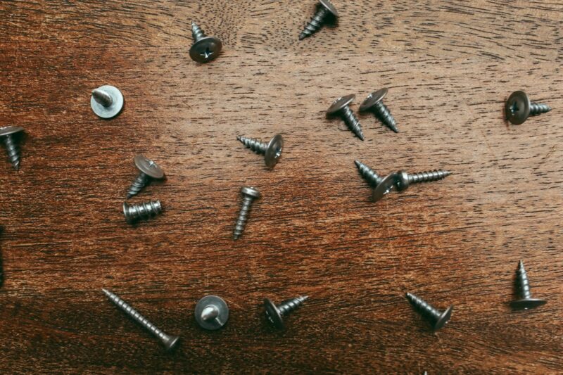 A detailed view of scattered screws on a wooden table for repair or DIY projects.