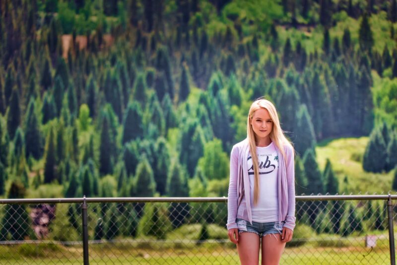 Portrait of a young woman by a fence with a mountainous backdrop in Silverton, Colorado