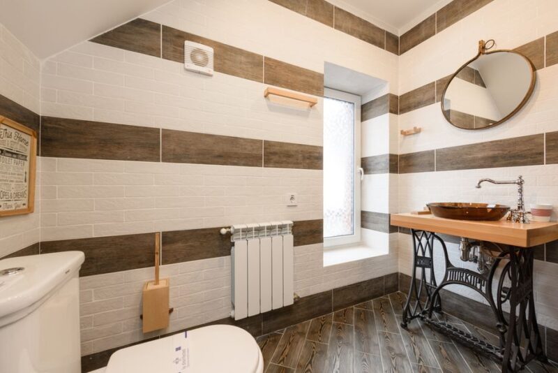 Elegant bathroom featuring a rustic wood vanity with natural grain and modern black fixtures, bathed in soft natural light.